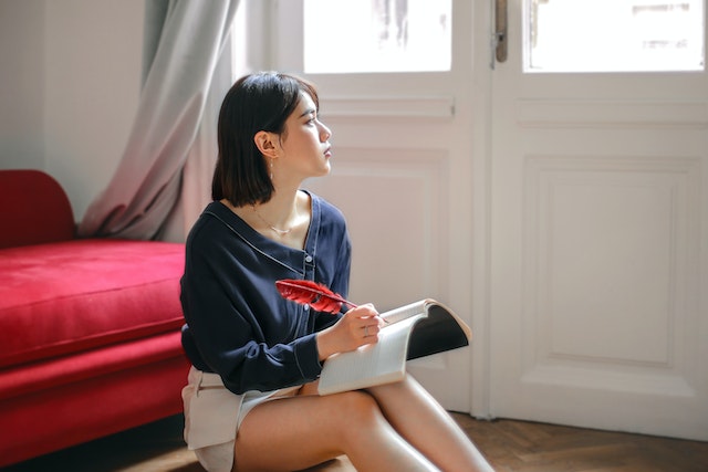 Picture of a woman writing something on a notebook.