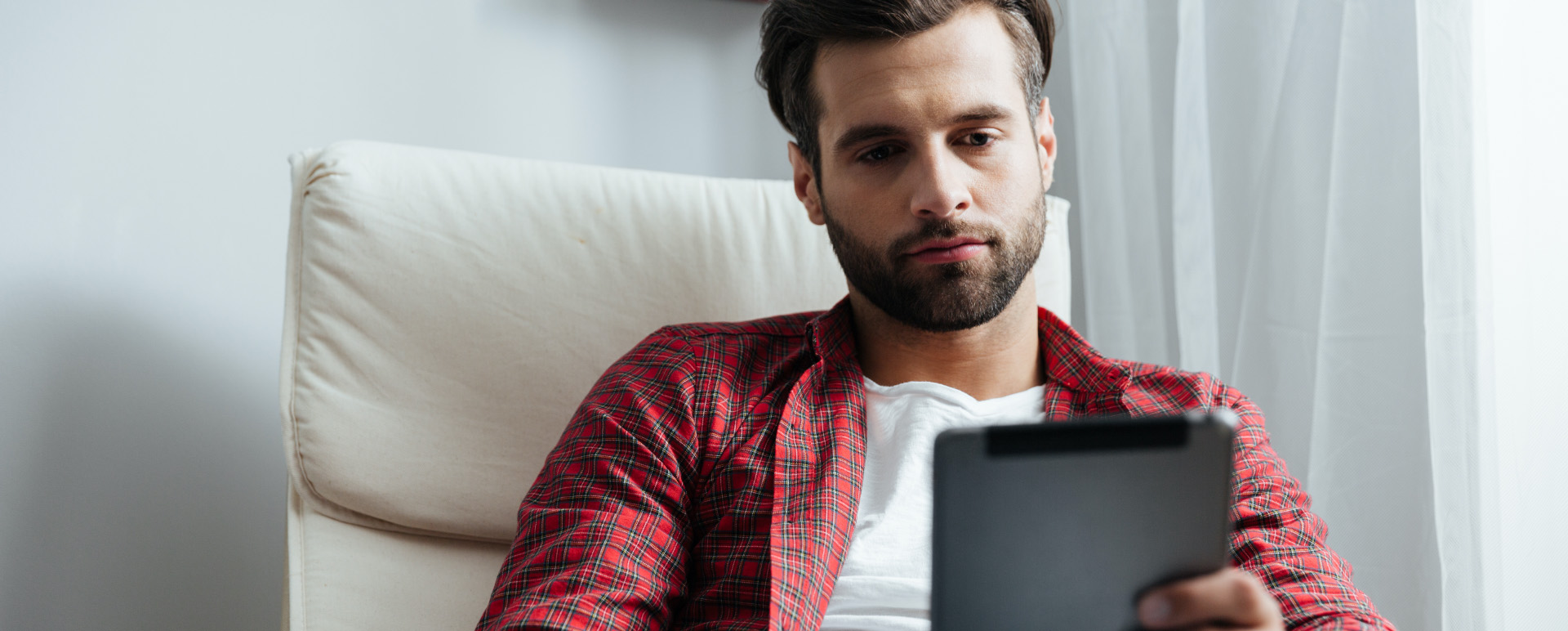 a man sitting holding and looking at a smartphone.